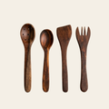Four dark brown wooden kitchen utensils, including a spoon, a spatula, a fork, and a perforated serving spoon, arranged vertically on a light cream background.