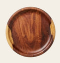 A round wooden serving platter with a rich dark brown center and contrasting light tan end grain, shown on a neutral light gray background.