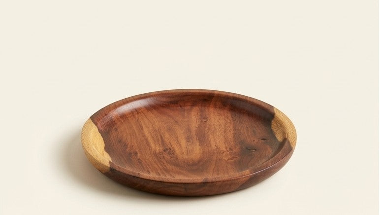 A round wooden serving tray with a dark brown grain pattern and light tan end caps, photographed on a solid off-white background.
