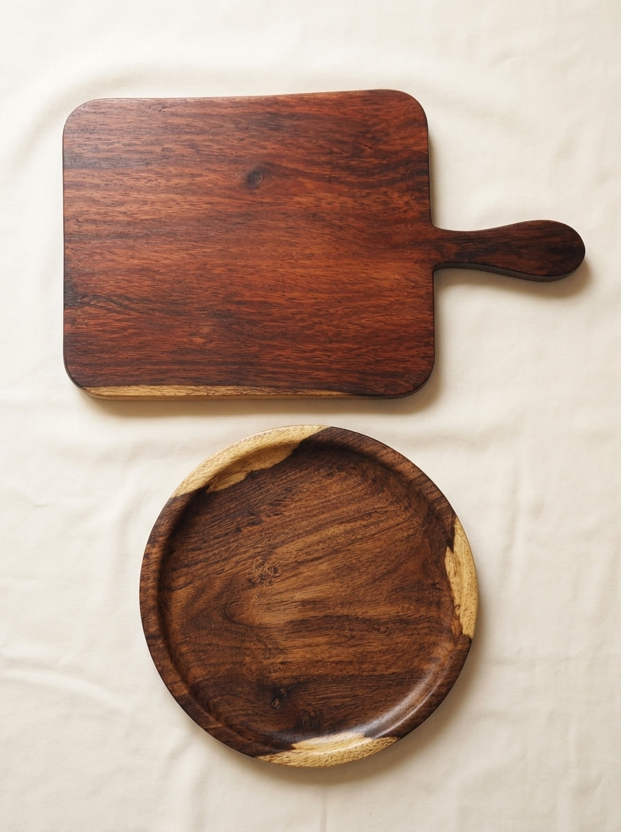 Two wooden serving boards, one rectangular with a handle and one round, displayed on a textured off-white fabric background.