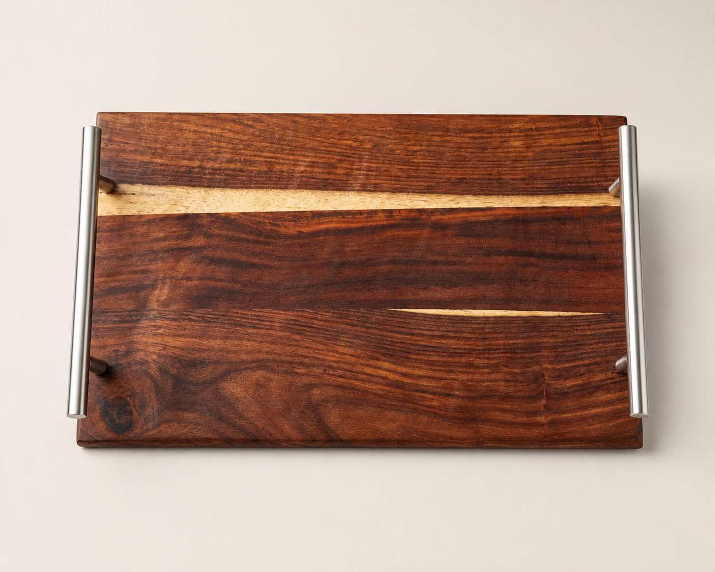 A rectangular wooden serving tray with a rich dark brown wood grain finish and a light natural wood inlay, featuring two cylindrical silver metal handles on the sides, set against a solid light beige background.
