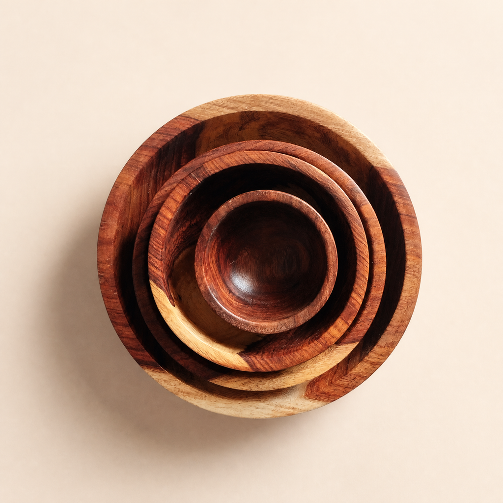 A set of five nested wooden bowls of varying sizes, showcasing natural wood grain patterns in shades of brown and beige, arranged on a solid light beige background.